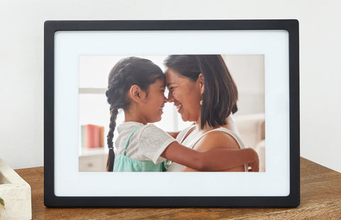 Close-up of the black 10-inch digital photo frame displaying a mother and daughter embracing. Shown as part of product listing for our 10-inch digital frame.